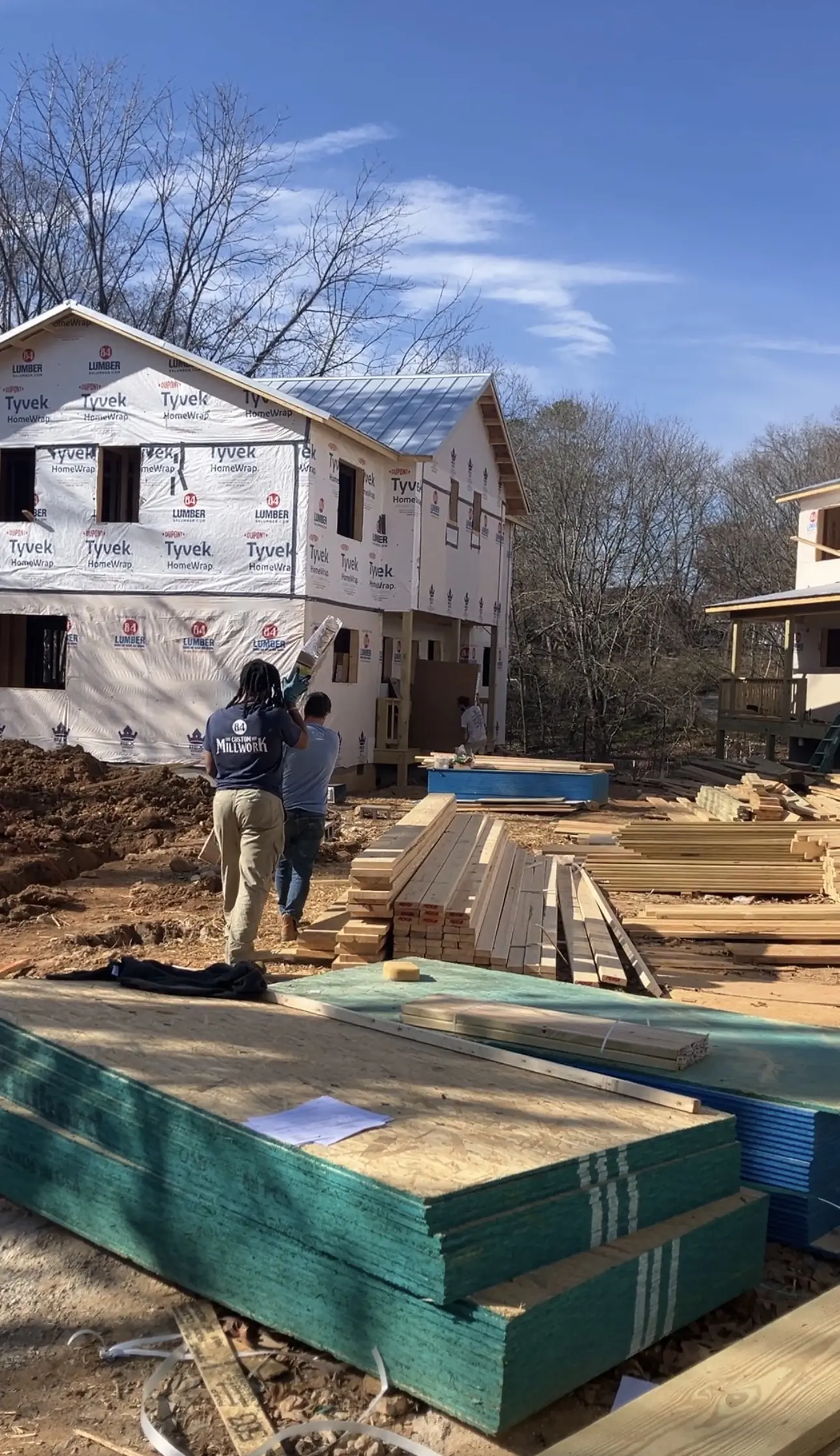 Construction crew and material stacks between homes