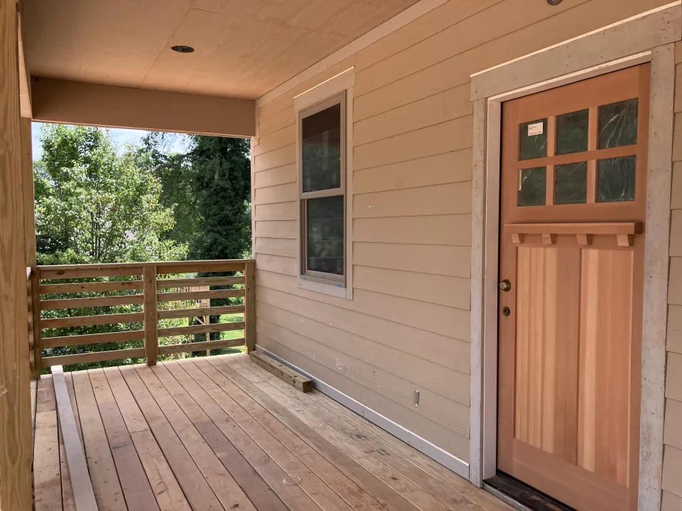 Covered wood deck beside a new exterior door