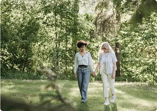 Two people walking together through a wooded landscape