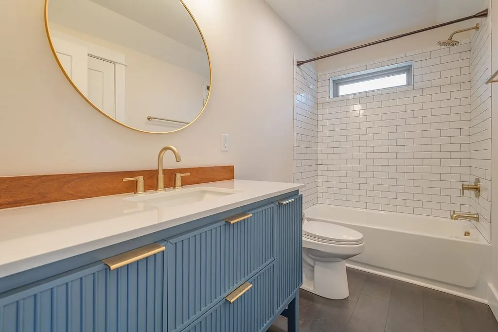 Bathroom with bathtub, tiled surround, and blue vanity