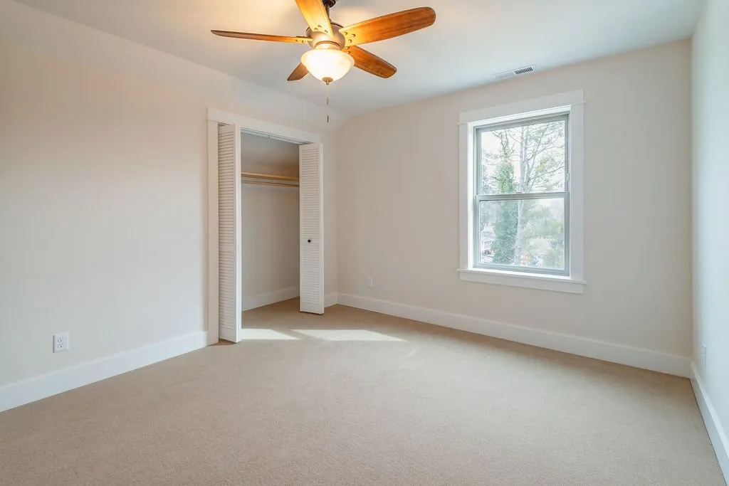Carpeted bedroom with a window and closet