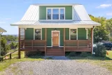 2024-built Green Built Gold home: covered front porch, metal roof, and cedar-tone railings
