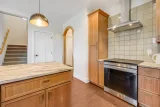 Induction range and tile backsplash; stairs to the second floor