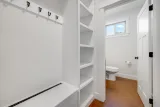 Mudroom bench, hooks, and built-in shelving beside the half bath