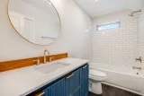 Hall bath: tub and shower with subway tile, fluted vanity, and brass fixtures