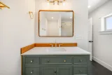 Primary bath vanity: quartz top, wood backsplash, and brass fixtures