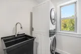 Dedicated laundry room: stacked washer and dryer included, utility sink, and storage